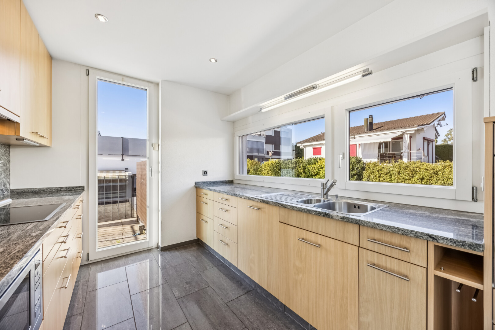 küche mit dark floor, light brown cabinets, hellbraune schränke, mikrowelle, und dark countertops