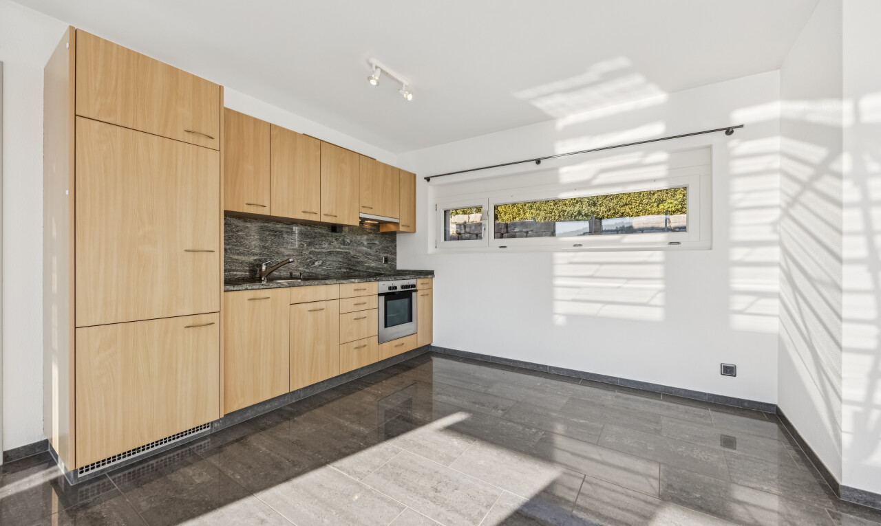 küche mit deckenbeleuchtung, dark countertops, light brown cabinets, hellbraune schränke, und flat panel cabinets