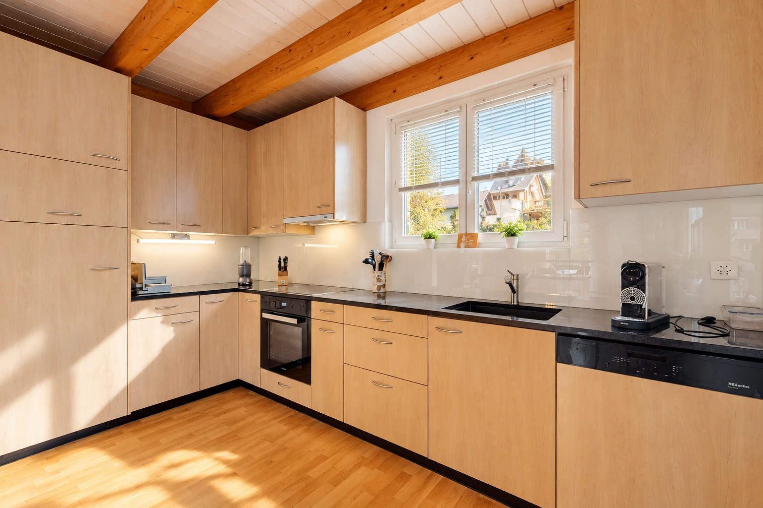 kitchen featuring dark countertops, dishwasher, light wood finish cabinetry, black oven, and light wood-style floors