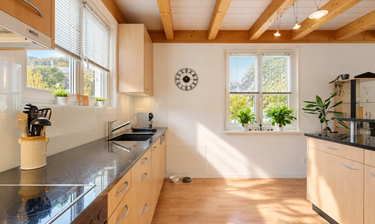 kitchen featuring beam ceiling, black electric cooktop, light wood finish cabinetry, range hood, and light wood-style flooring