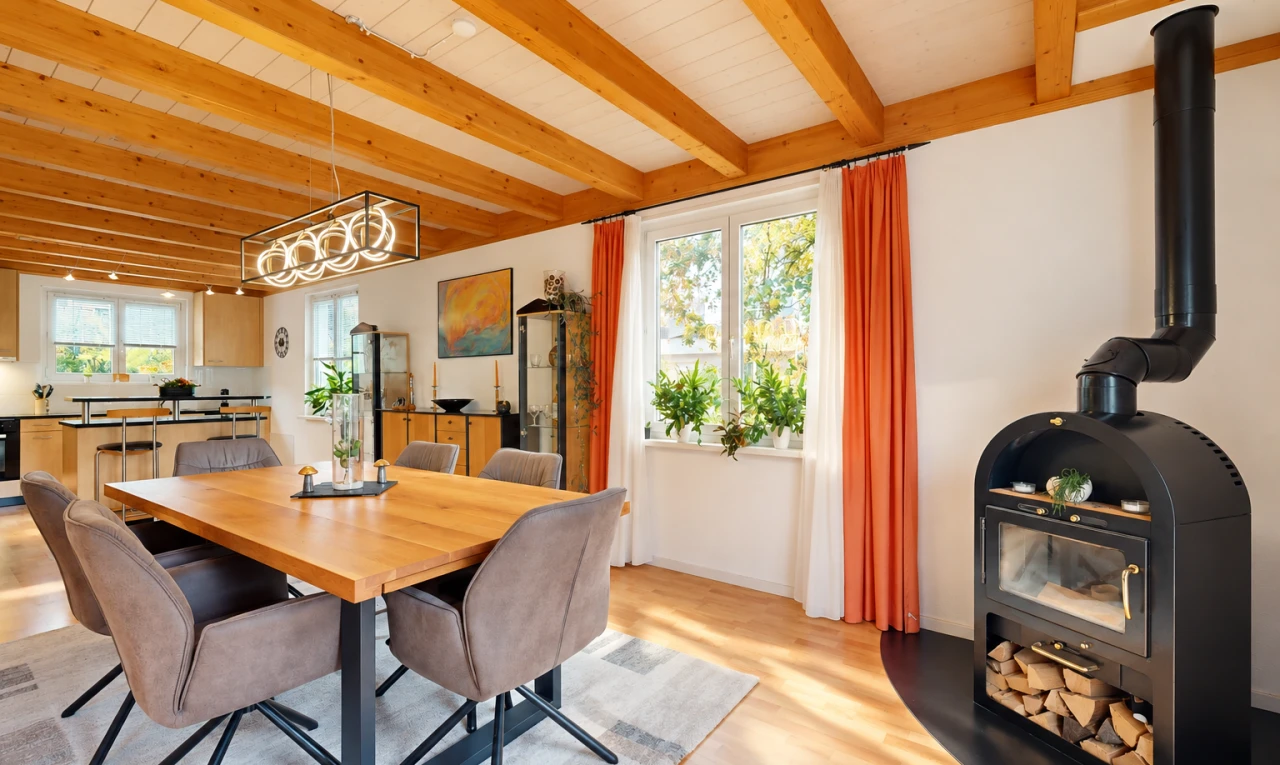 dining room featuring a wood stove, light wood finished floors, and a wood ceiling with exposed beams