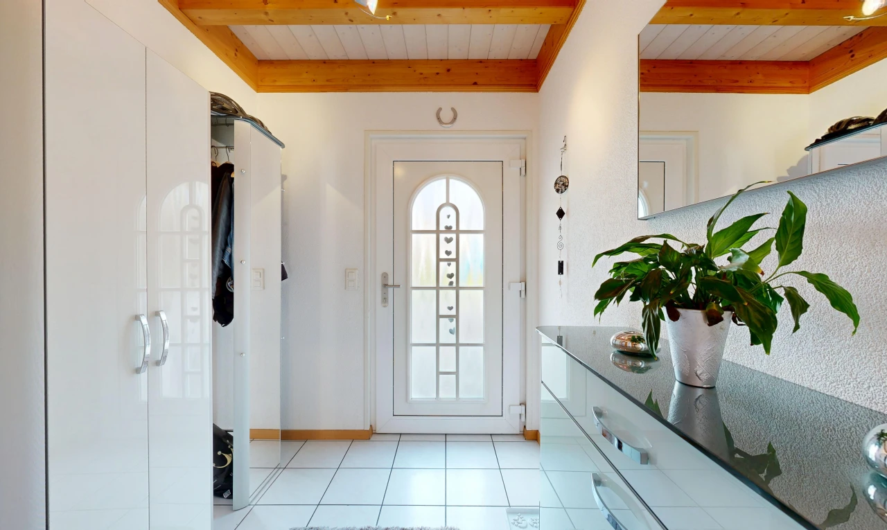 corridor featuring access to outside, light tile patterned floors, and beam ceiling