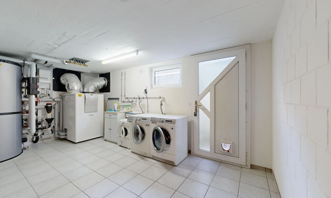 laundry room with washing machine and clothes dryer, concrete block wall, light tile patterned flooring, and heating unit