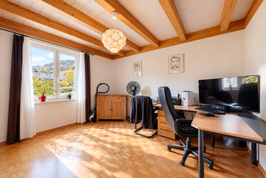 bureau avec plafond à poutres, beamed ceiling, télévision, sol en finition bois, et wood finish floor