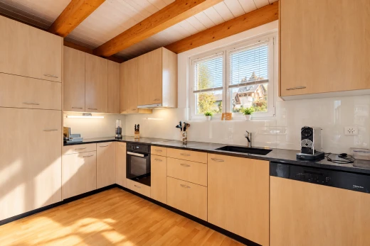 kitchen featuring dark countertops, dishwasher, light wood finish cabinetry, black oven, and light wood-style floors