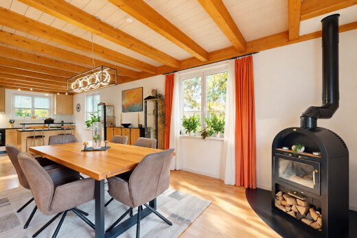 salle à manger avec poêle à bois, beamed ceiling, plafond à poutres, lumière naturelle, et wood finish floor