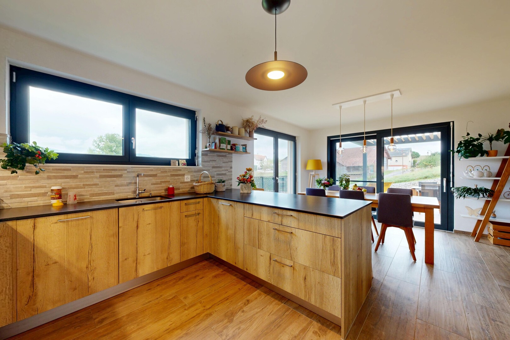 kitchen with a peninsula, hanging light fixtures, modern cabinets, light wood-style flooring, and dark countertops