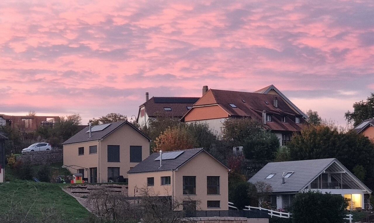 outdoor house at dusk with solar panels, a patio, a residential view, and stucco siding