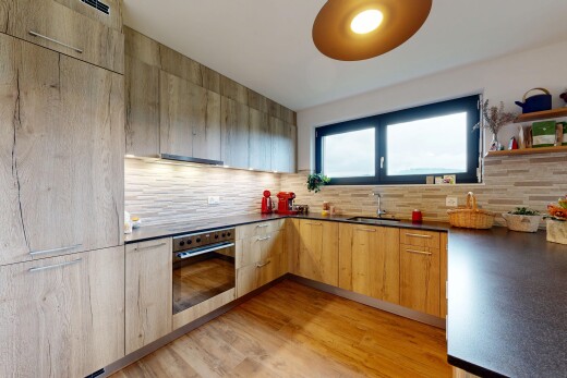 cuisine avec armoires à panneau plat, sol en finition bois, wood finish floor, four, et lumière naturelle