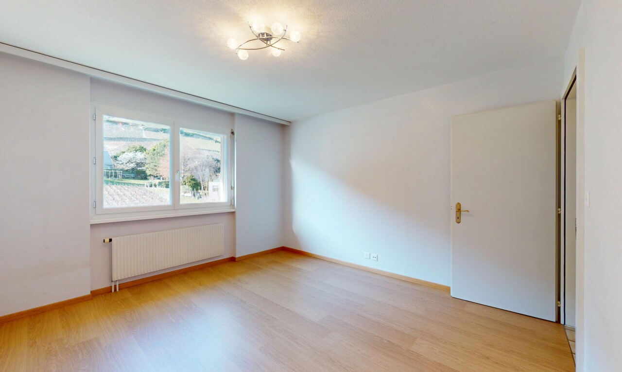 pièce vide avec lumière naturelle, radiateur, cloison sèche, et sol en finition bois