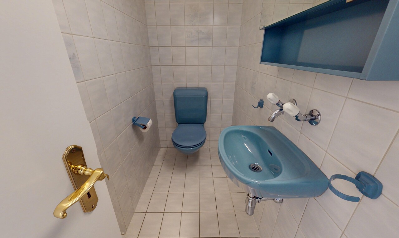 salle de bains avec évier, mur en carrelage, et toilette