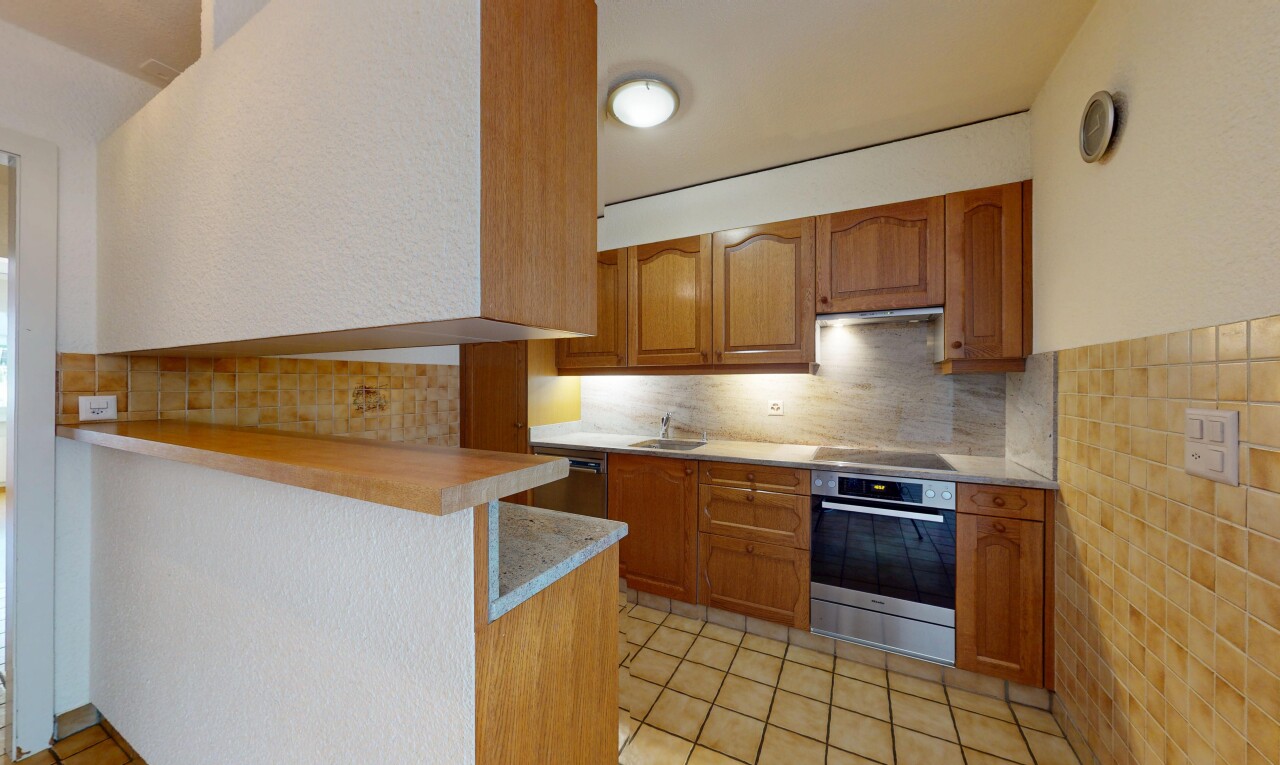 cuisine avec armoires marron moyen, four, plaque de cuisson, plans de travail, et armoires en arc