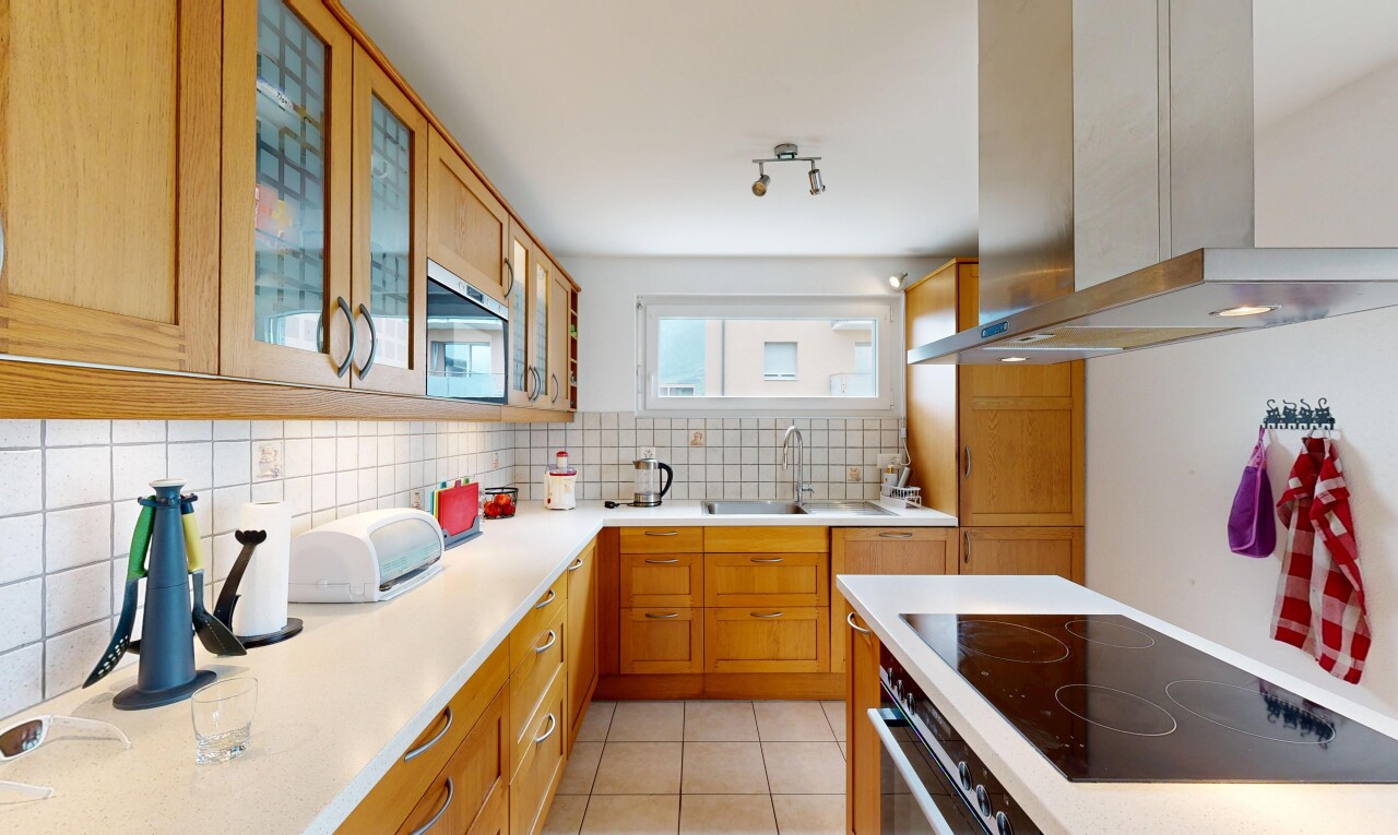 cuisine avec hotte, backsplash, dosseret, light countertops, et armoires marron moyen