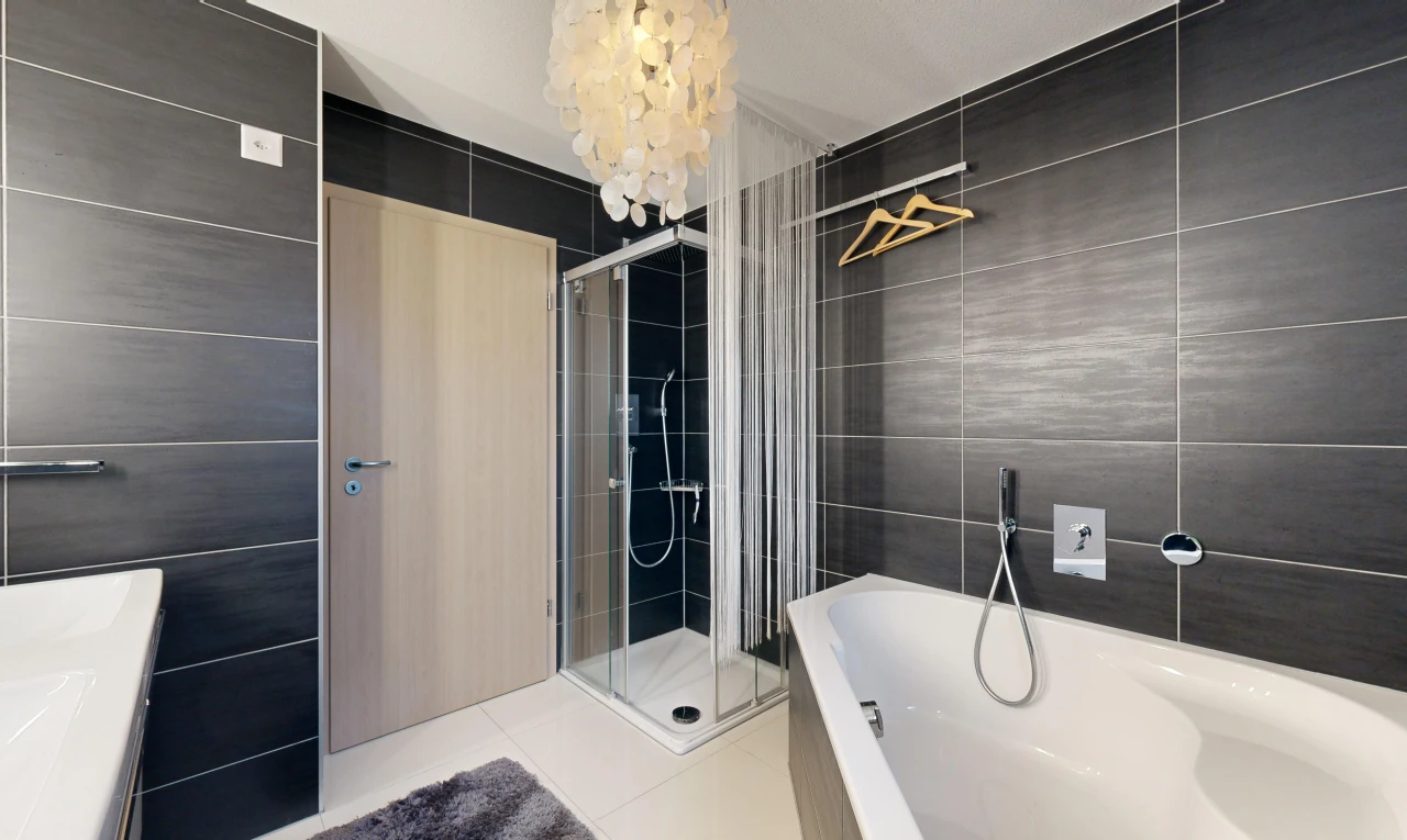 bathroom with tile patterned flooring, shower with separate bathtub, an inviting chandelier, and tile walls