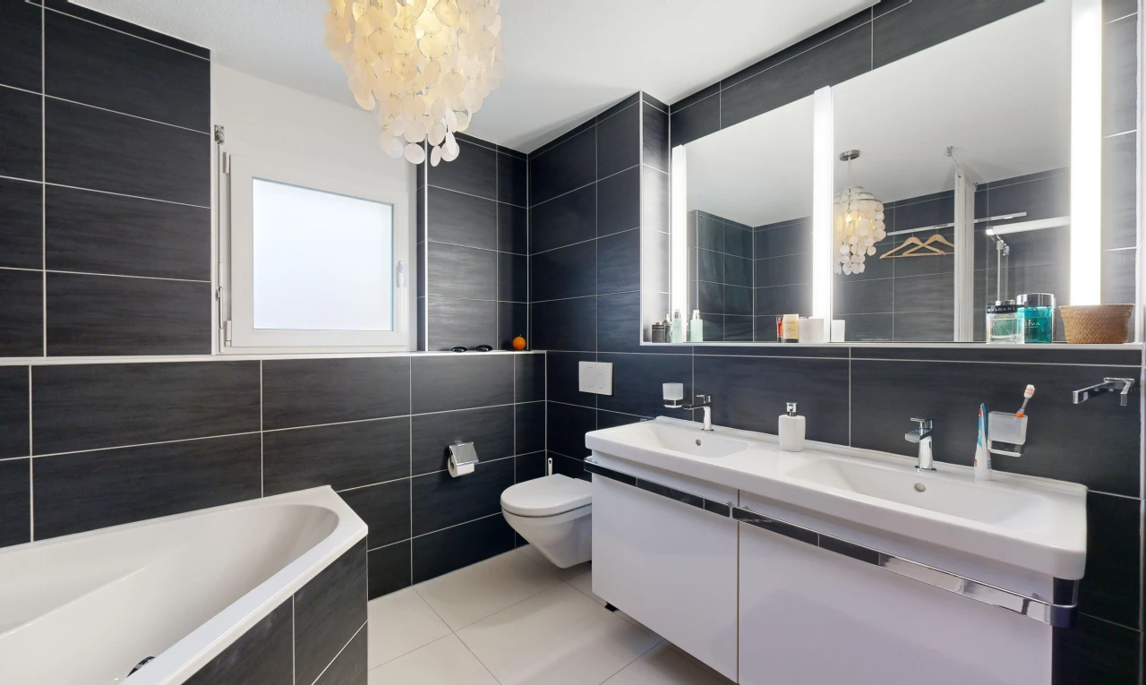 bathroom featuring vanity, tiled tub, an inviting chandelier, tile walls, and tile patterned flooring