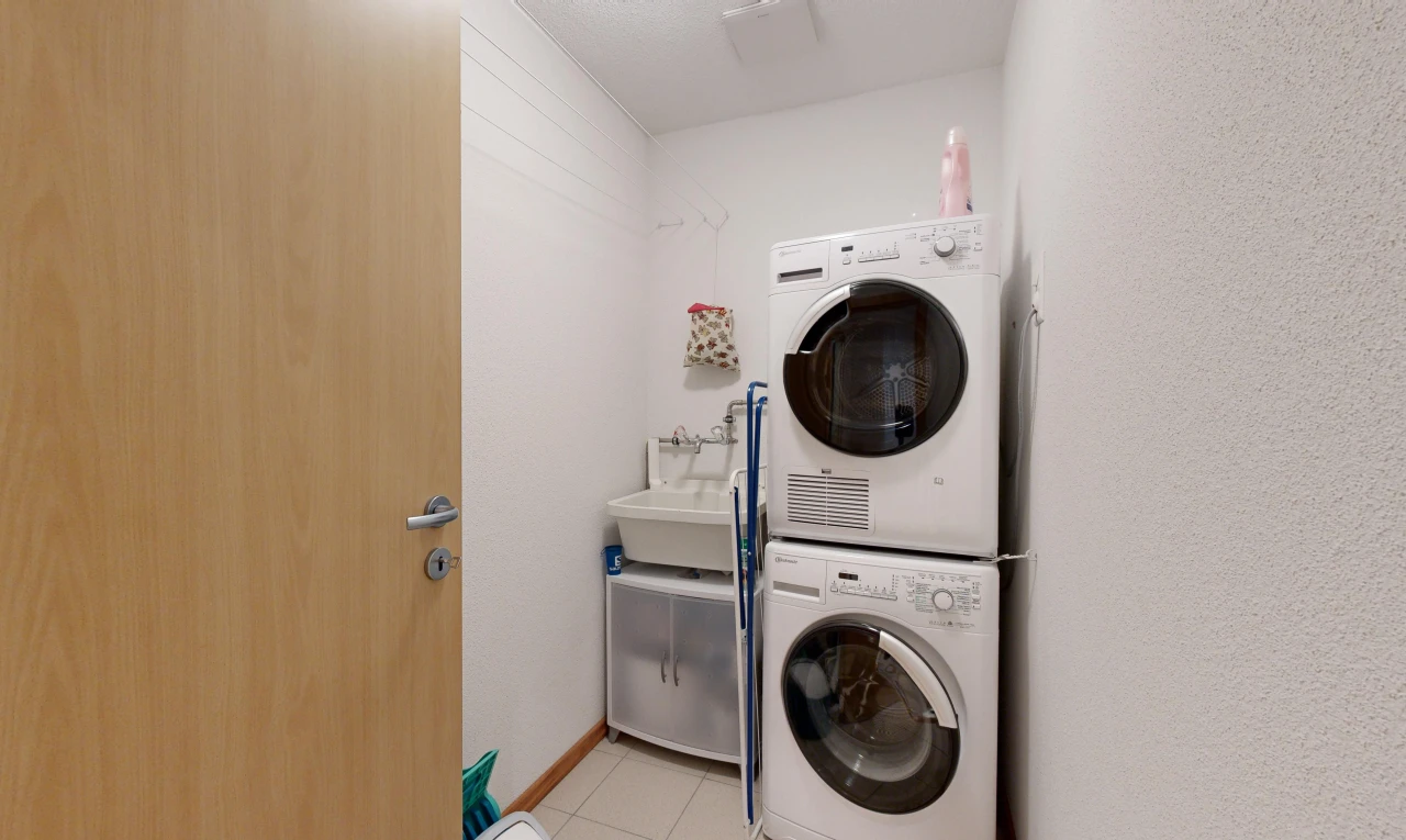 washroom with light tile patterned floors, sink, and stacked washer and clothes dryer