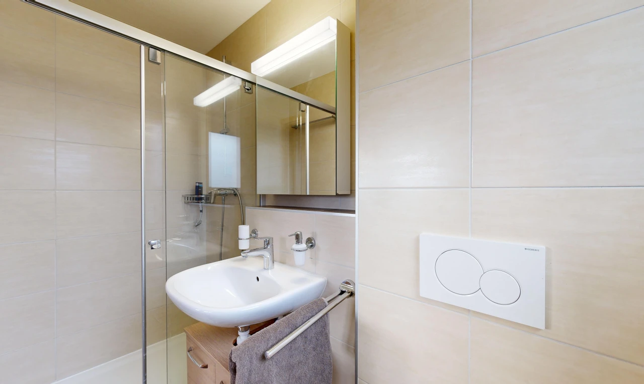 bathroom featuring backsplash, sink, a shower with door, and tile walls