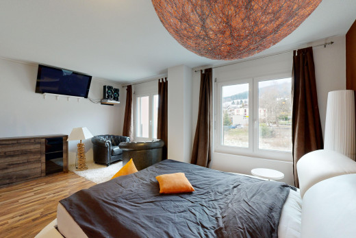 chambre avec lumière naturelle, télévision, et plancher de bois