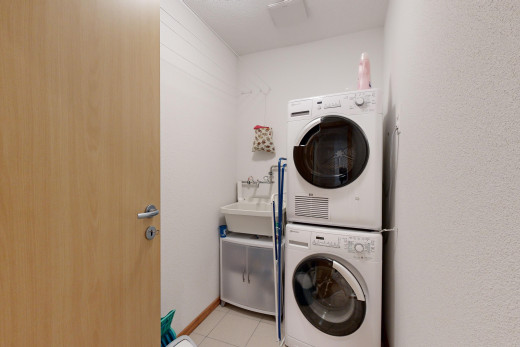 buanderie avec vasque, machine à laver / sèche-linge superposés, carrelage, et buanderie