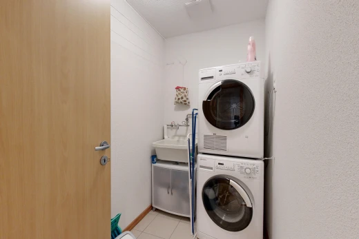 buanderie avec vasque, machine à laver / sèche-linge superposés, carrelage, et buanderie