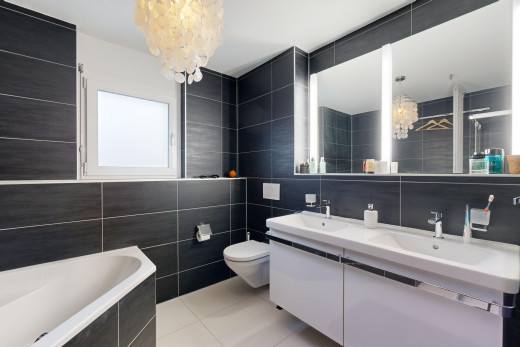 salle de bains avec carrelage, vasque, meuble-lavabo, lustre, et mur carrelé