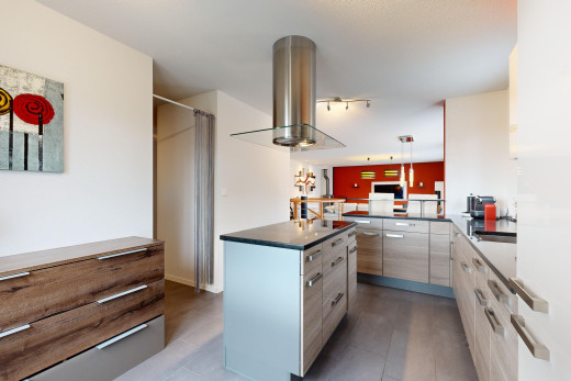 cuisine avec plan de travail, îlot de cuisine, hotte, suspension, et meubles à panneaux plats