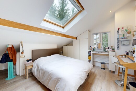 chambre avec lumière naturelle, plafond voûté, puits de lumière, sol en finition bois, et pièce supplémentaire