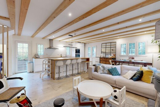 salon avec plafond à poutres, sol en finition bois, lumière naturelle, et éclairage encastré