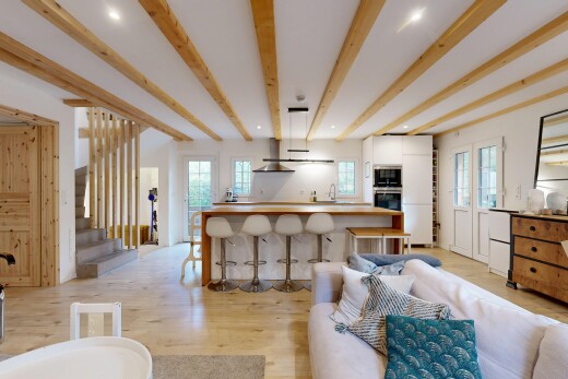 salon avec lumière naturelle, escaliers, plafond à poutres, et sol en finition bois