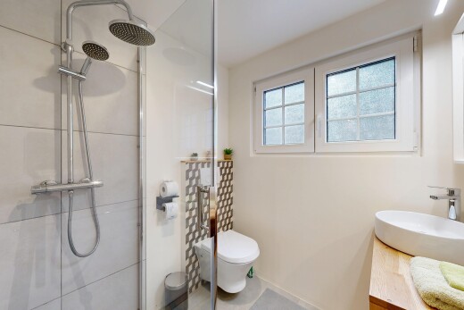 salle de bains avec lavabo (ou coiffeuse selon le contexte), évier, lumière naturelle, et douche