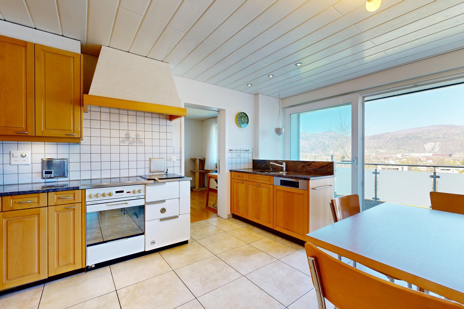 cuisine avec dark countertops, hotte, light floor, medium brown cabinets, et armoires marron moyen