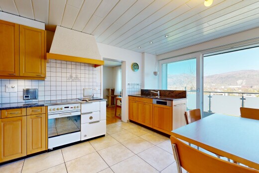 cuisine avec dark countertops, hotte, light floor, medium brown cabinets, et armoires marron moyen