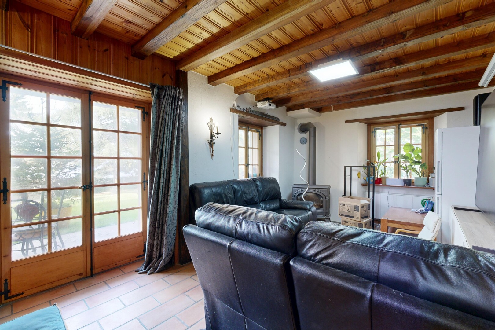 salon avec plafond en bois, wood ceiling, plafond à poutres, beamed ceiling, et poêle à bois