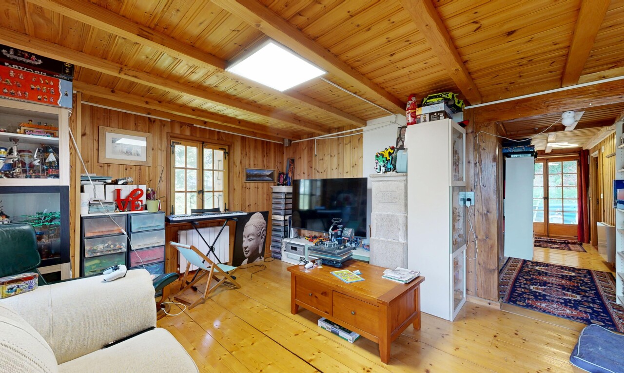 salon avec plafond à poutres, beamed ceiling, portes-fenêtres, dated wood wall, et télévision