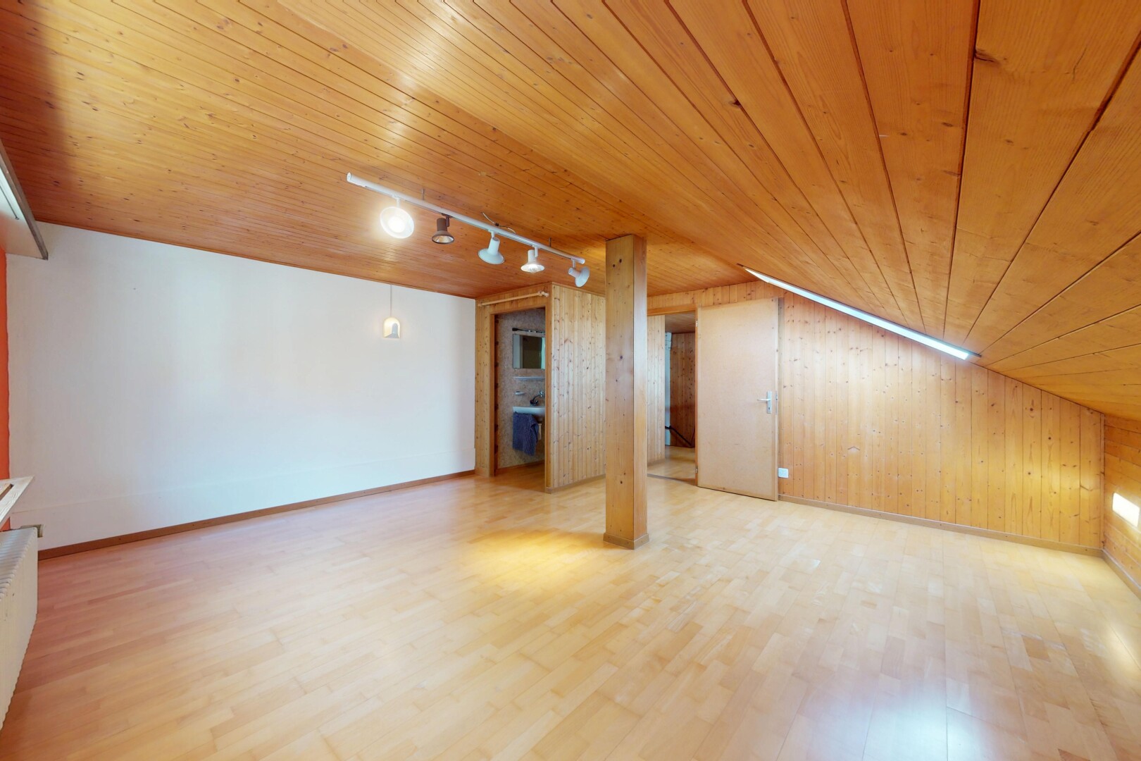 pièce vide avec track lighting, éclairage sur rail, wood wall, mur en bois, et sous-sol