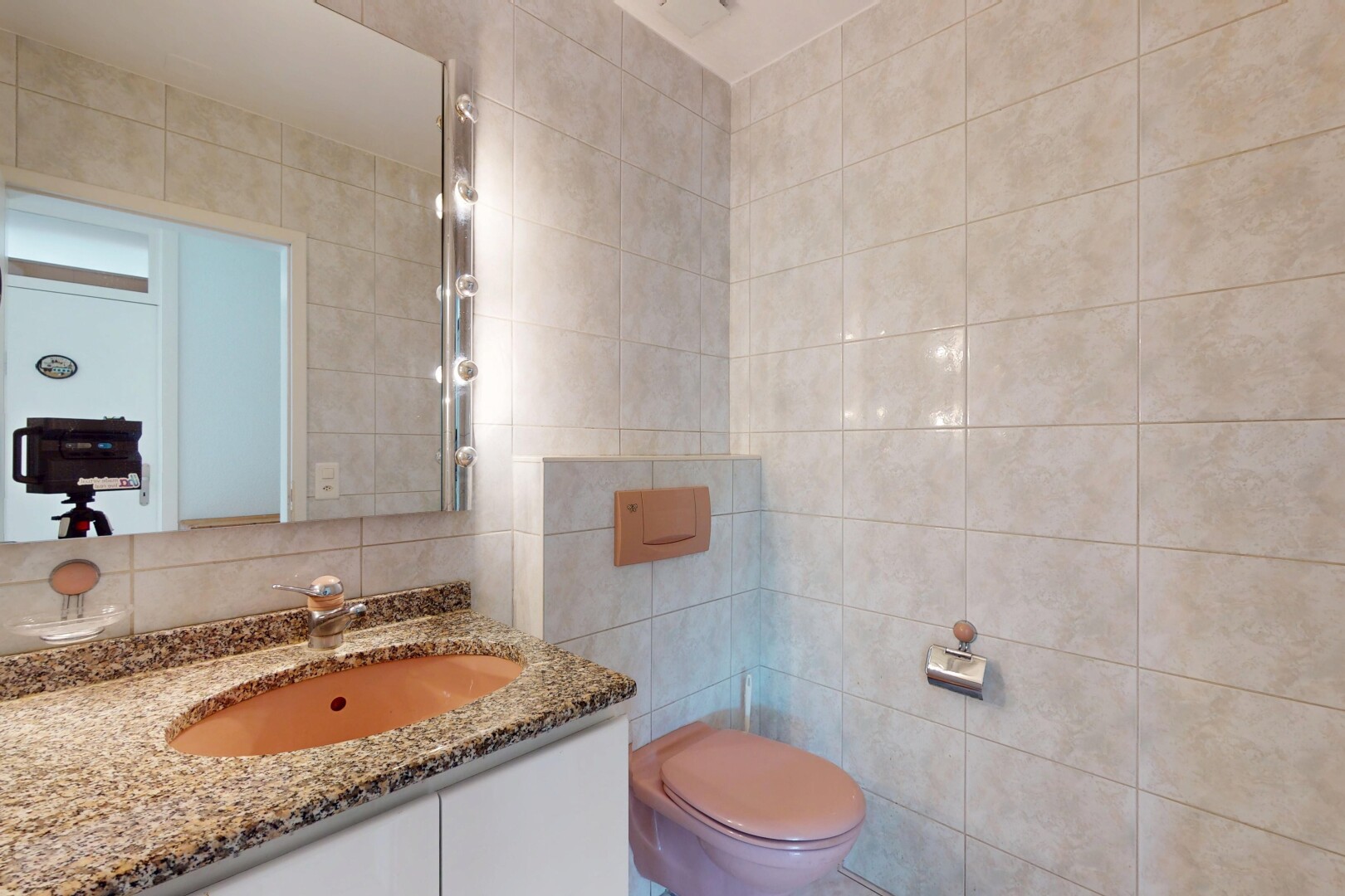 salle de bains avec mur en carrelage, tile wall, toilette, miroir, et lavabo (ou coiffeuse selon le contexte)
