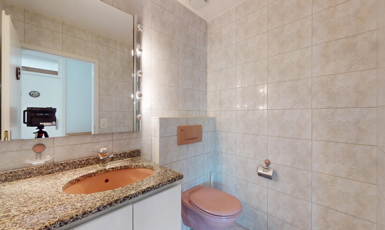 salle de bains avec mur en carrelage, tile wall, toilette, miroir, et lavabo (ou coiffeuse selon le contexte)