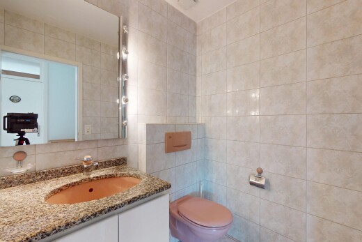 salle de bains avec mur en carrelage, tile wall, toilette, miroir, et lavabo (ou coiffeuse selon le contexte)