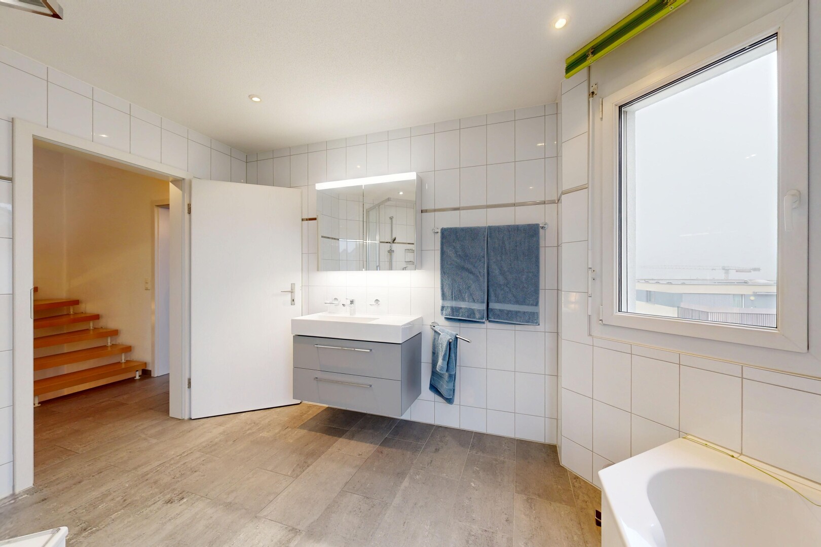 salle de bains avec mur en carrelage, tile wall, salle de bain complète, lavabo (ou coiffeuse selon le contexte), et lumière naturelle