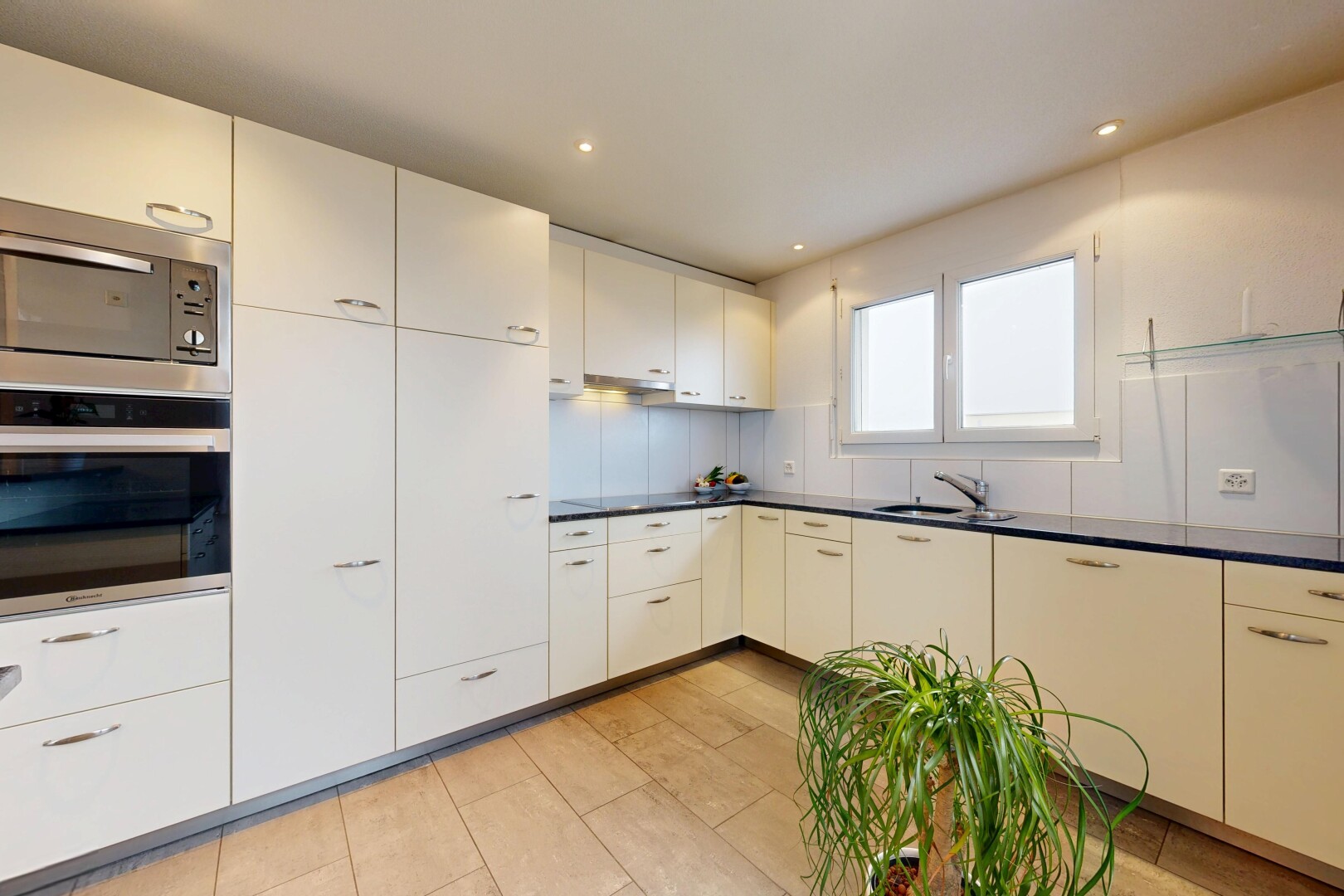 cuisine avec four, micro-ondes, dark countertops, plans de travail, et lumière naturelle