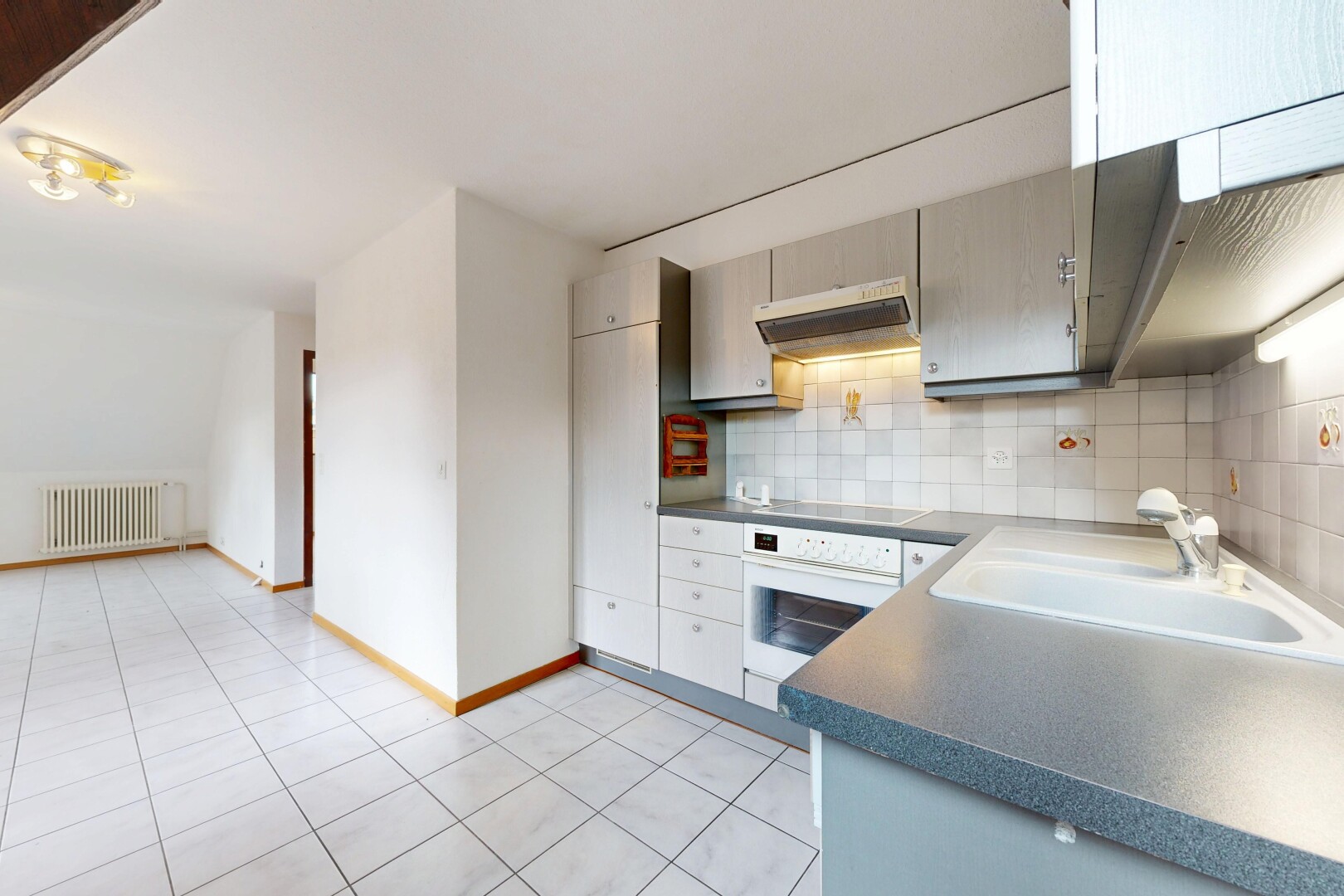 cuisine avec light floor, plans de travail, dark countertops, hotte, et four