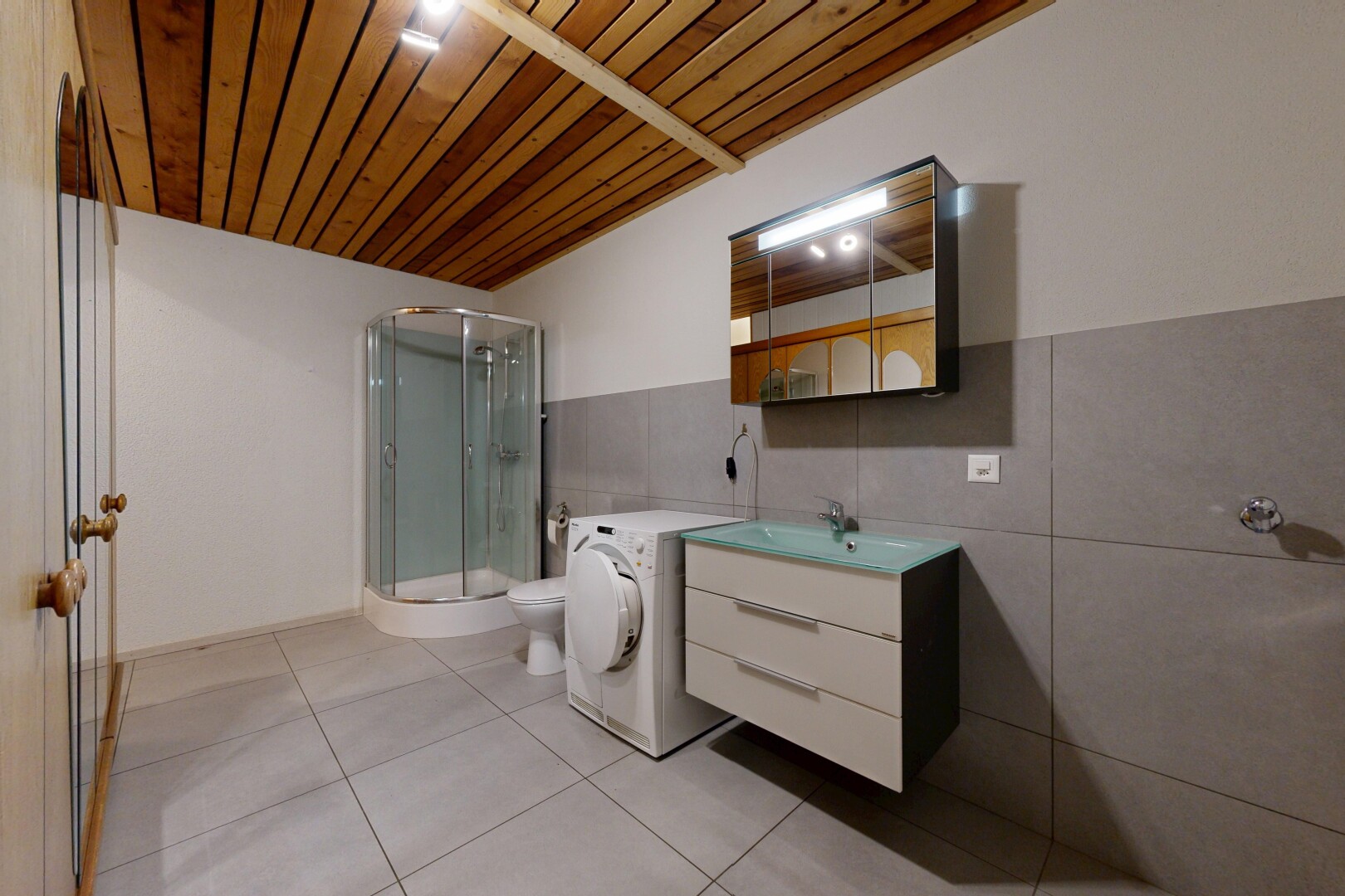 salle de bains avec douche, lavabo (ou coiffeuse selon le contexte), salle de bain complète, miroir, et toilette