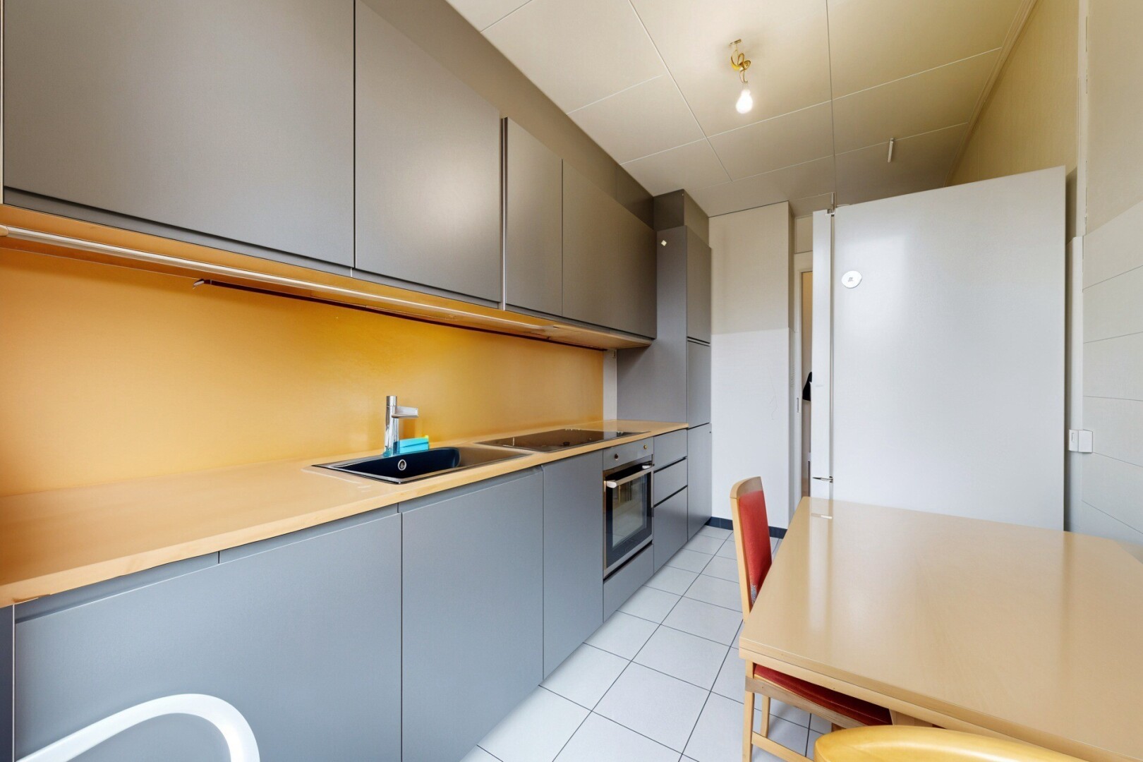 cuisine avec armoires grises, gray cabinets, light floor, réfrigérateur, et armoires à panneau plat
