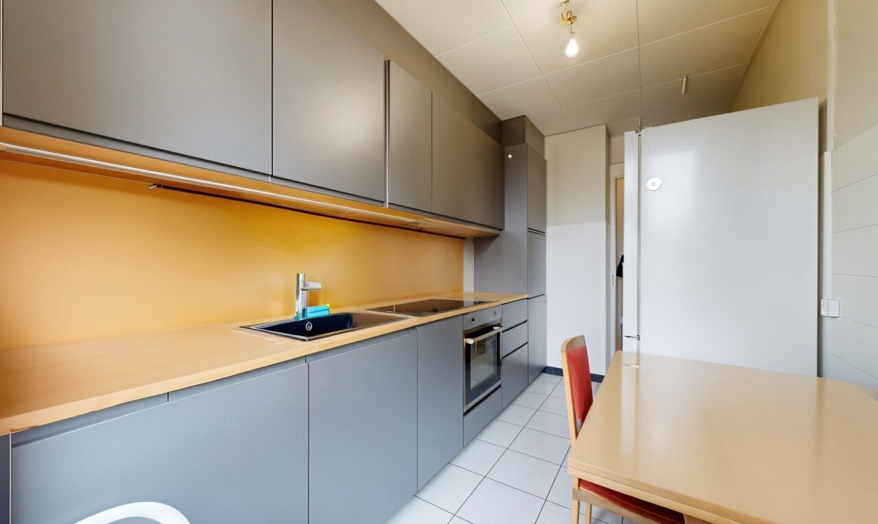 cuisine avec armoires grises, gray cabinets, light floor, réfrigérateur, et armoires à panneau plat