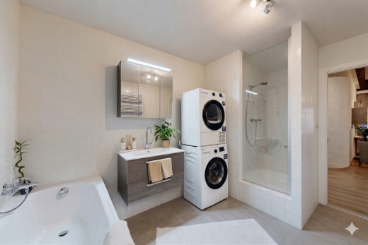 salle de bains avec light floor, miroir, lavabo (ou coiffeuse selon le contexte), mur en carrelage, et tile wall