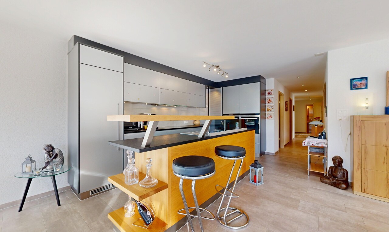 cuisine avec bar de cuisine, armoires grises, cloison sèche, drywall, et inside property