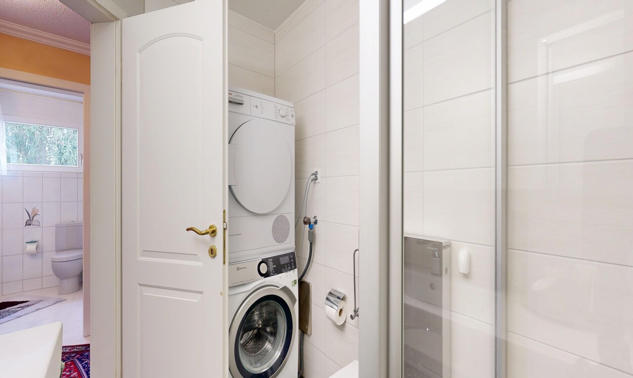 laundry area featuring tile walls, stacked washer / dryer, and crown molding