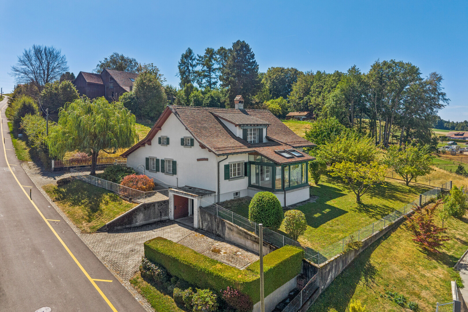 façade avec property visible, toit mansardé, garage intégré, cheminée, et drone view