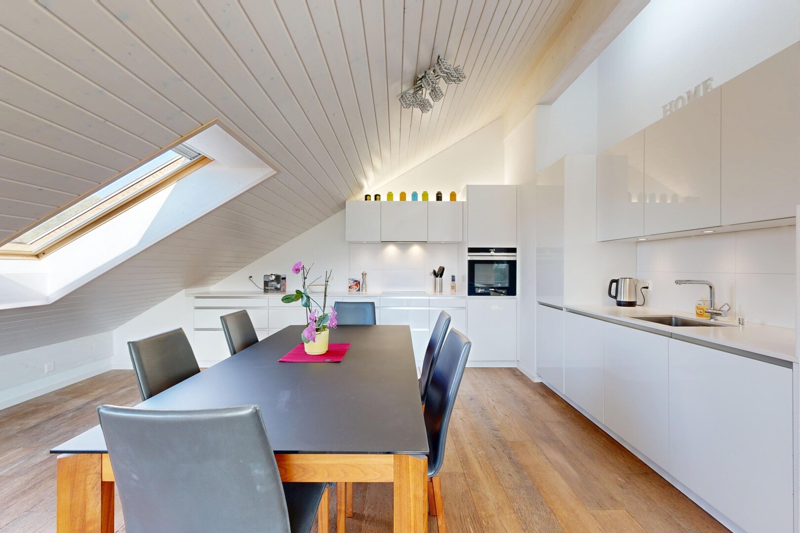 cuisine avec puits de lumière, flat panel cabinets, armoires à panneau plat, vaulted ceiling, et plafond voûté