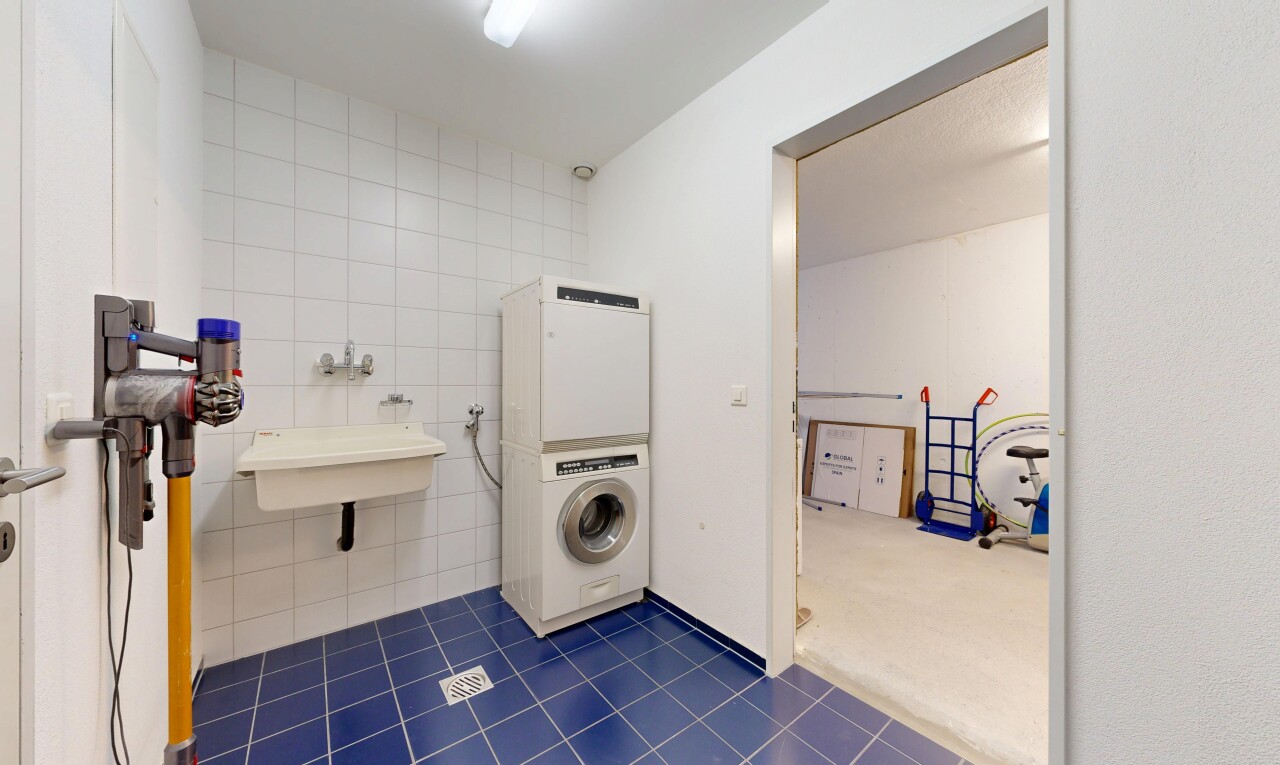 buanderie avec lave-linge et sèche-linge, mur en carrelage, tile wall, inside property, et dark floor
